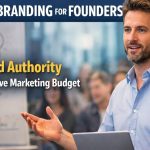Founder presenting ideas to an audience with a laptop and whiteboard, illustrating personal branding and authority-building without a large marketing budget.